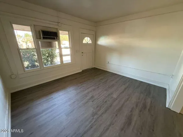 an empty room with wooden floor and windows