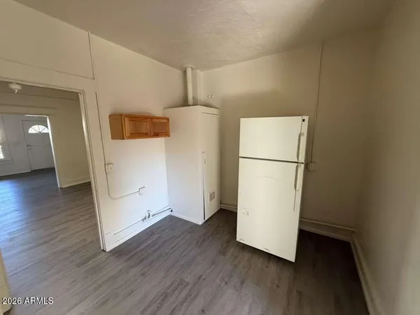 a view of a refrigerator in kitchen and an empty room