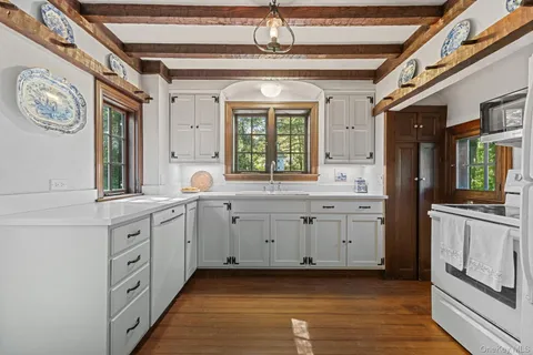 a kitchen with granite countertop a sink stainless steel appliances a large window and a refrigerator