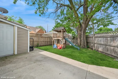 a view of a house with a small yard and a large tree