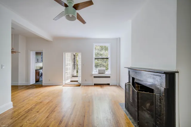 a view of an empty room with window and wooden floor