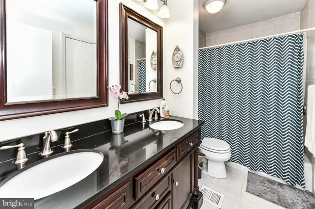 a bathroom with a granite countertop toilet a sink and a mirror
