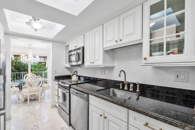 a kitchen with granite countertop a sink and a stove next to a large window