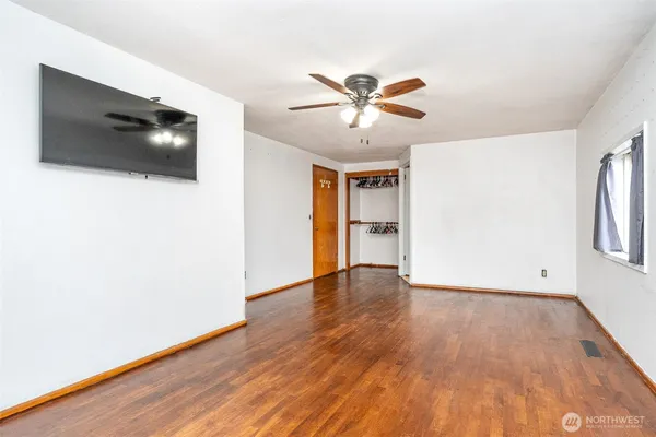 a view of an empty room with wooden floor and a window