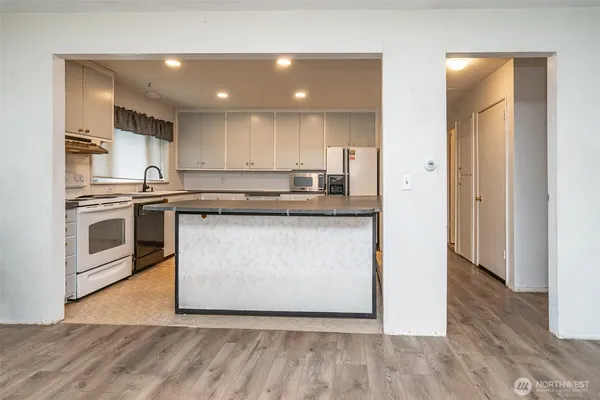 a kitchen with stainless steel appliances granite countertop a stove top oven a sink and white cabinets