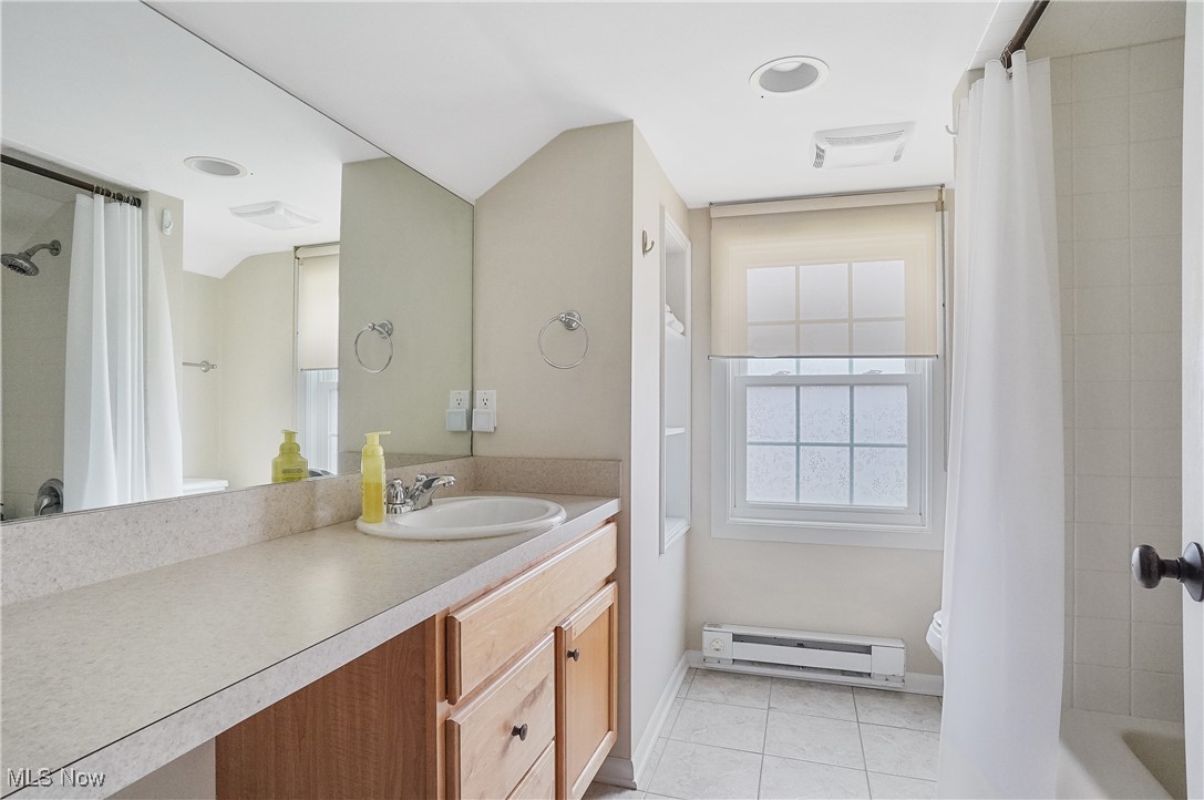 33825 Cannon Road Solon, OH 44139 - Photo 31 of 44 Master bath with visible vents, vanity, a baseboard heating unit, shower / bath combo with shower curtain, and tile patterned flooring