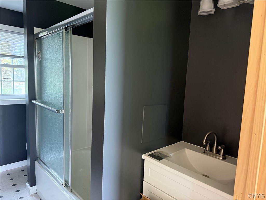 7167 Ferstler Road Manlius, NY 13082 - Photo 4 of 8 A modern vanity sits adjacent to a glass-enclosed tub shower in this bathroom.