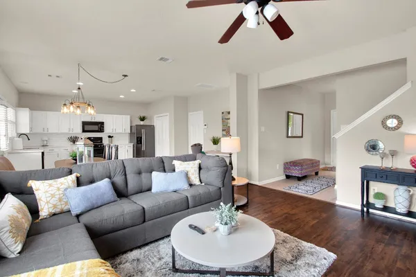 a living room with furniture kitchen view and a chandelier