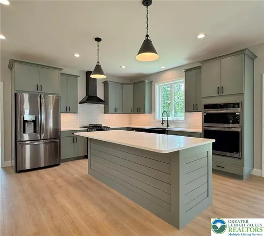 a kitchen with stainless steel appliances granite countertop a sink a stove and a wooden floors