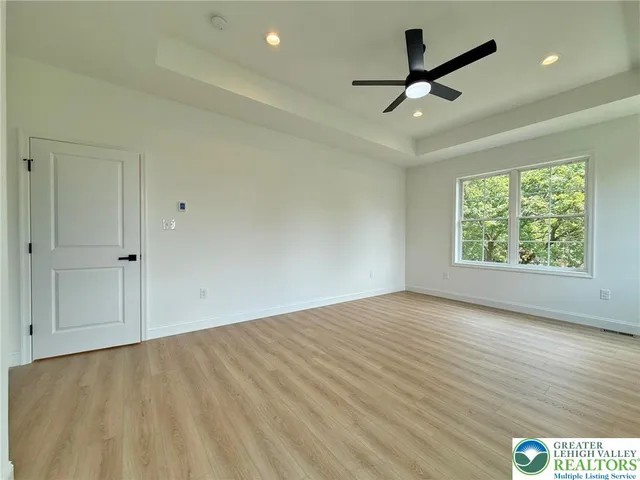 an empty room with wooden floor ceiling fan and windows