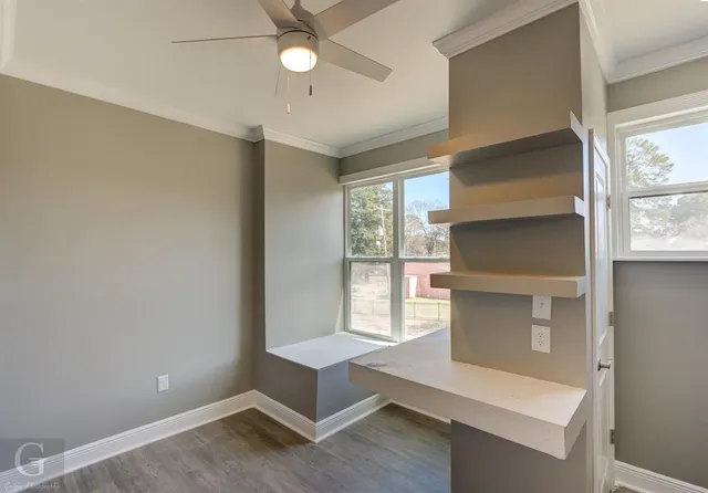 a view of an empty room with a window and wooden floor