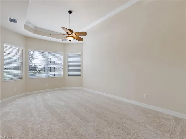 an empty room with windows and ceiling fan