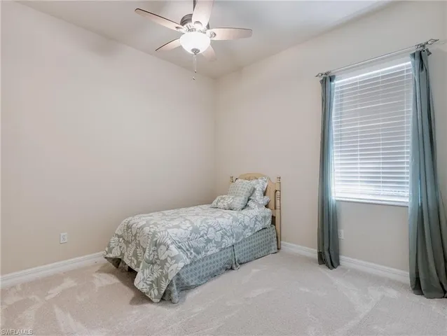 a bed sitting in a bedroom next to a window and a chandelier