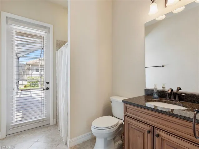 a bathroom with a granite countertop toilet a sink and a mirror