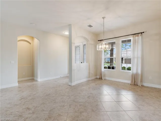 a view of an empty room with window and chandelier fan