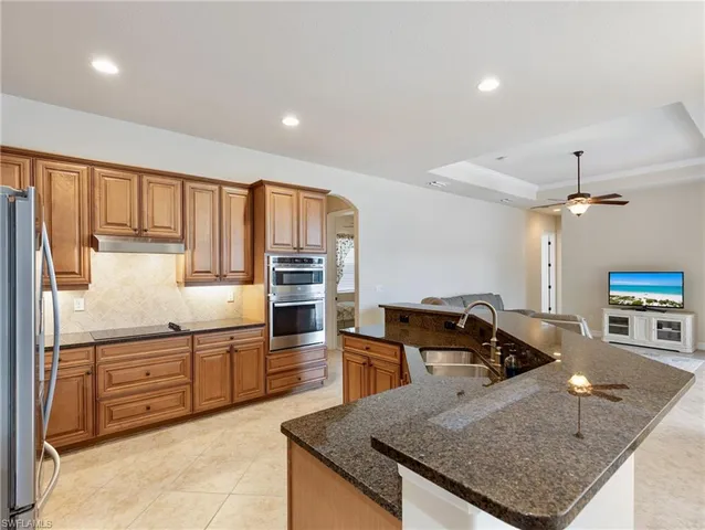 a kitchen with stainless steel appliances granite countertop a sink a stove and a refrigerator