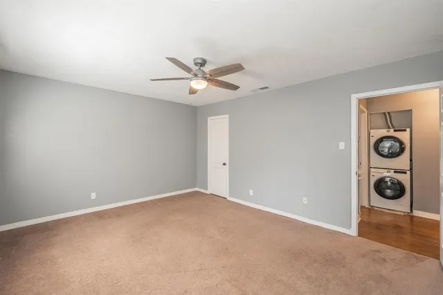 a view of an empty room with window and ceiling fan