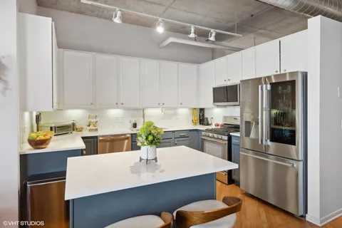 a kitchen with a refrigerator a stove a sink and white cabinets with wooden floor