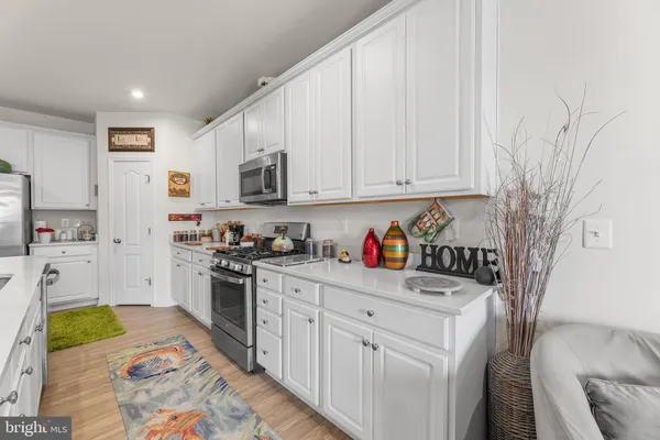a kitchen with stainless steel appliances granite countertop a refrigerator sink and white cabinets