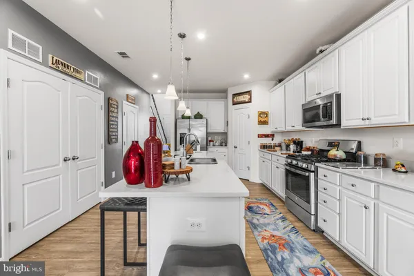 a very nice looking kitchen with stainless steel appliances granite countertop a stove a sink dishwasher and a refrigerator with wooden floor