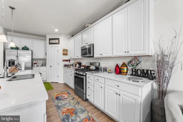 a kitchen with stainless steel appliances granite countertop a stove a sink dishwasher and white cabinets with wooden floor