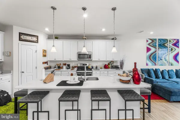 a kitchen with stainless steel appliances kitchen island granite countertop a table chairs stove and white cabinets