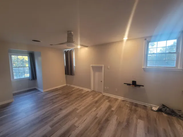 an empty room with wooden floor and windows