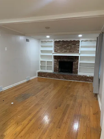 a view of empty room with wooden floor and fireplace