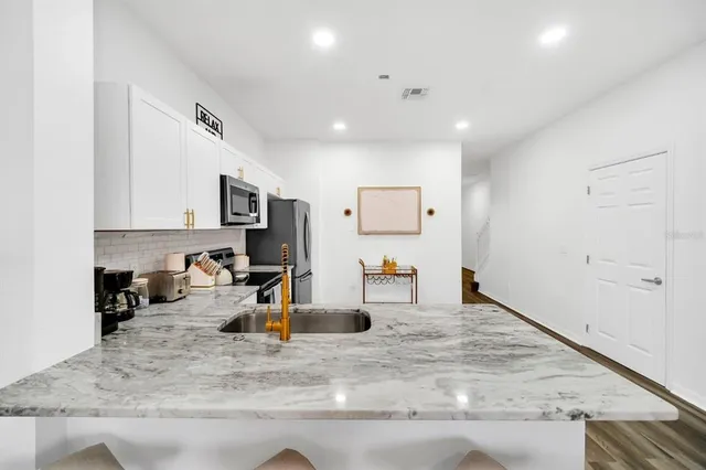 a view of a kitchen with a sink dishwasher stove and cabinets
