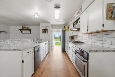 a large kitchen with granite countertop a sink and stove top oven
