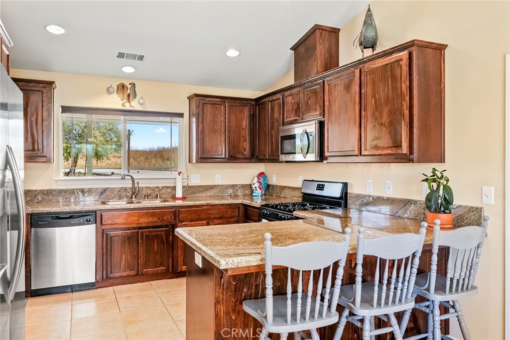 5950 Forked Horn Place Paso Robles, CA 93446 - Photo 5 of 31 a kitchen with stainless steel appliances granite countertop a stove top oven a sink dishwasher a dining table and chairs with wooden floor