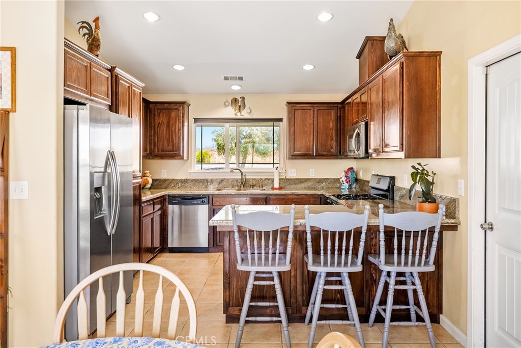 5950 Forked Horn Place Paso Robles, CA 93446 - Photo 8 of 31 a kitchen with stainless steel appliances granite countertop a dining table chairs refrigerator and sink