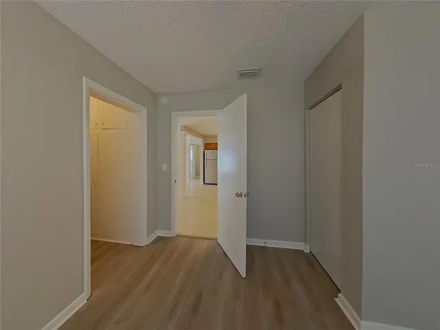 a view of an empty room with wooden floor and closet