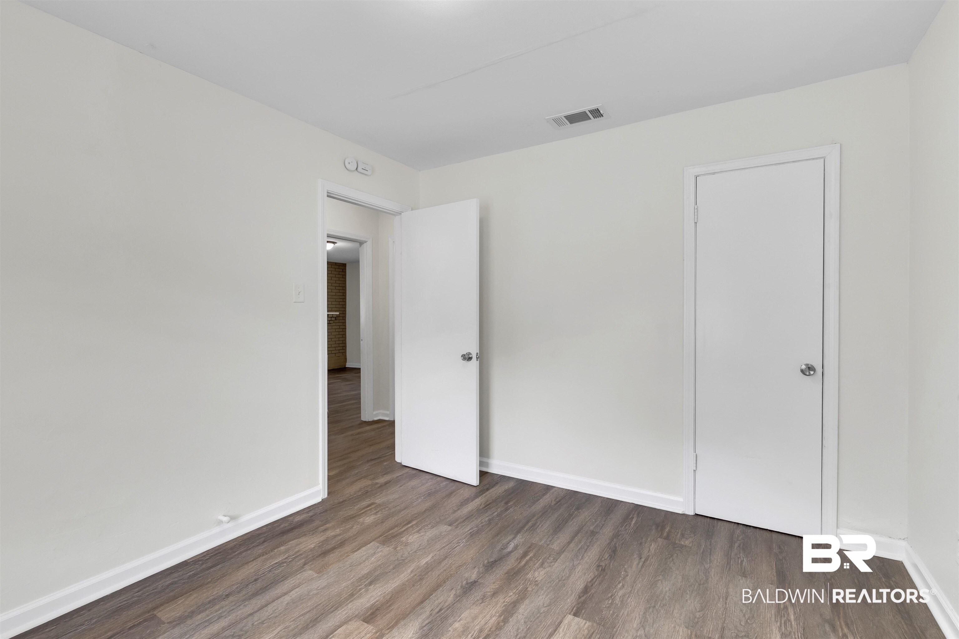 9241 Vallaris Street North Mobile, AL 36608 - Photo 7 of 17 Unfurnished bedroom featuring visible vents, baseboards, and wood finished floors