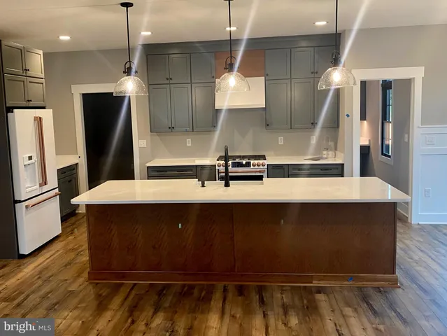a kitchen with kitchen island a sink stainless steel appliances and wooden floor