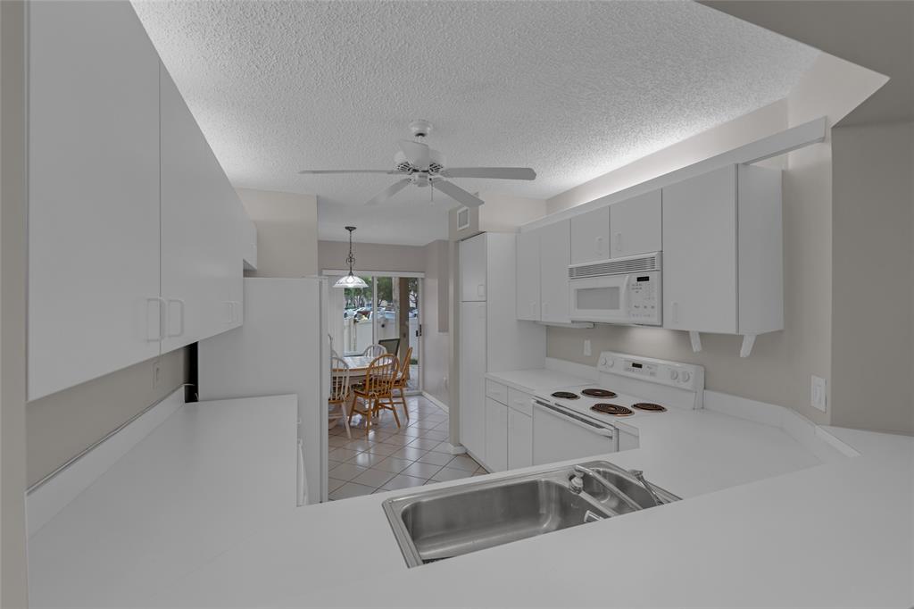 9599 Weldon Circle, Unit 103A Tamarac, FL 33321 - Photo 16 of 26 a kitchen with granite countertop a sink a stove and cabinets