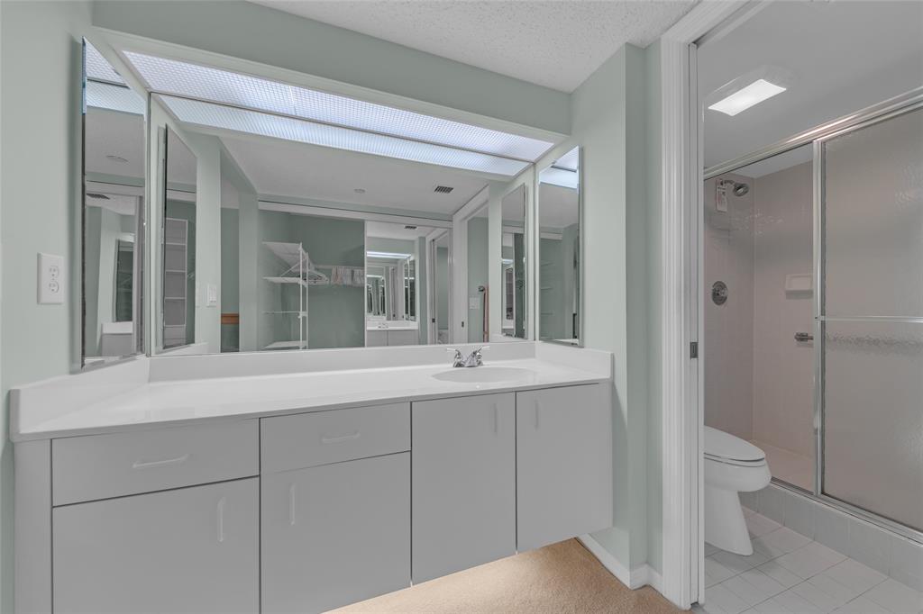 9599 Weldon Circle, Unit 103A Tamarac, FL 33321 - Photo 22 of 26 a bathroom with a sink and mirror with toilet