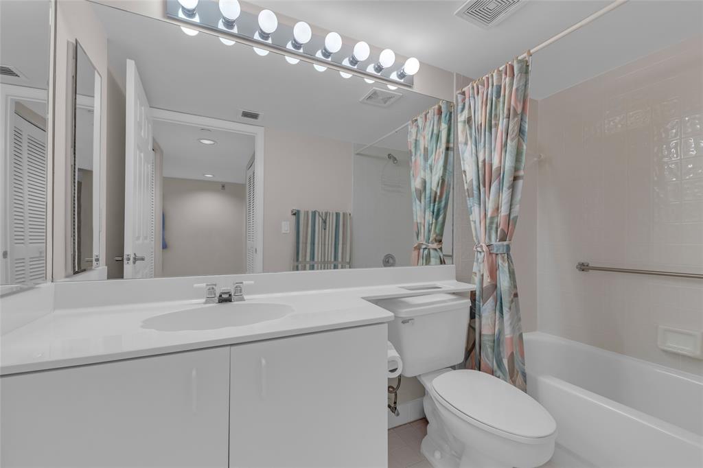 9599 Weldon Circle, Unit 103A Tamarac, FL 33321 - Photo 24 of 26 a bathroom with a sink a toilet a mirror a bathtub and shower