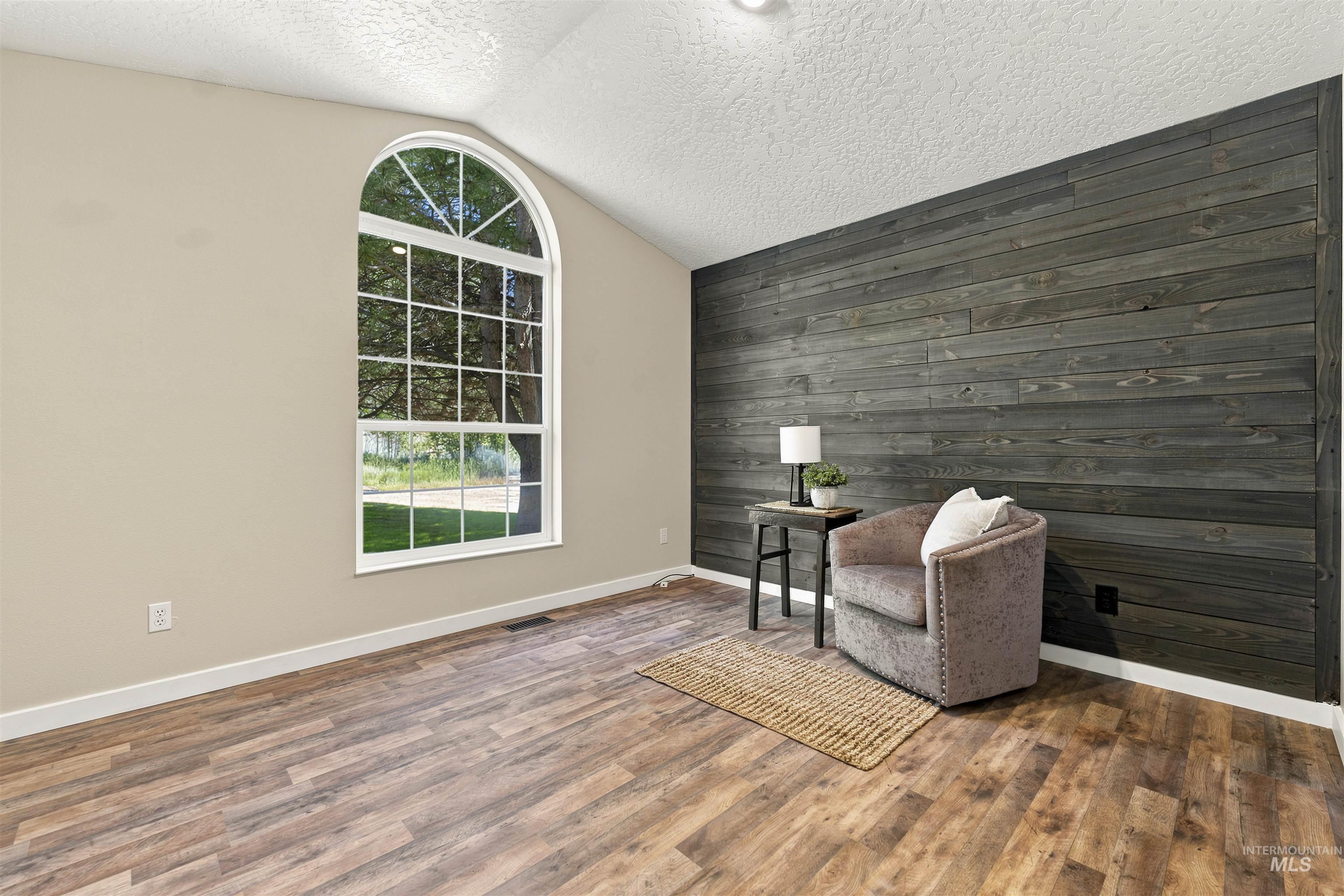 24864 Coventry Drive Caldwell, ID 83607 - Photo 21 of 49 Room featuring an arched window, wood-finish flooring, and a textured accent wall