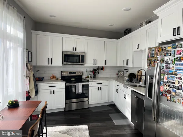 a kitchen with granite countertop a sink stainless steel appliances and white cabinets