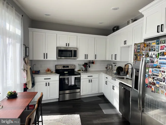 a kitchen with granite countertop a sink stainless steel appliances and white cabinets