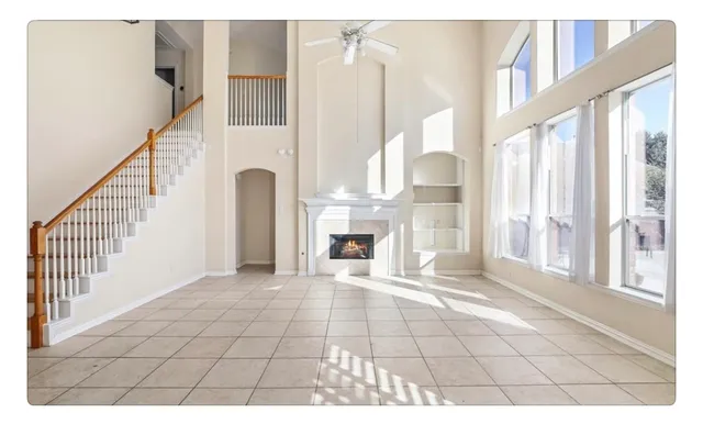 a view of an empty room with wooden floor and a fireplace