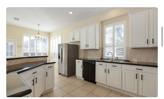 a kitchen with granite countertop white cabinets and stainless steel appliances
