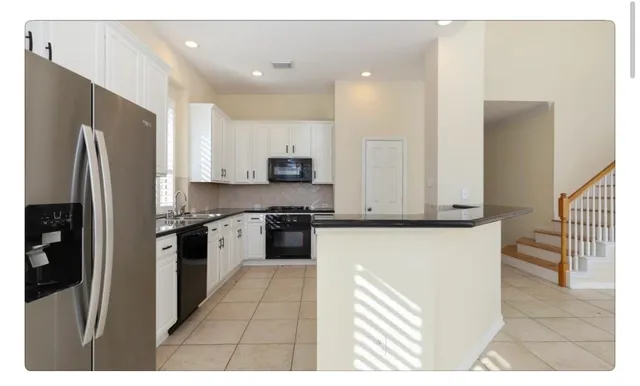 a kitchen with stainless steel appliances kitchen island granite countertop a refrigerator a stove and a sink