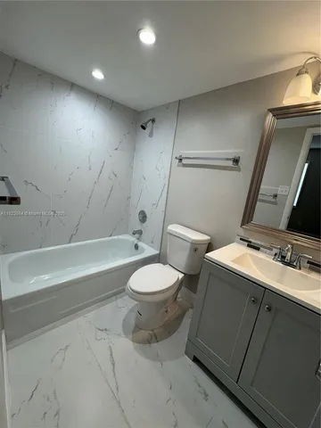 a white toilet sitting next to a bathroom sink and vanity