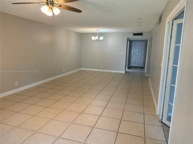 a view of an empty room and chandelier fan