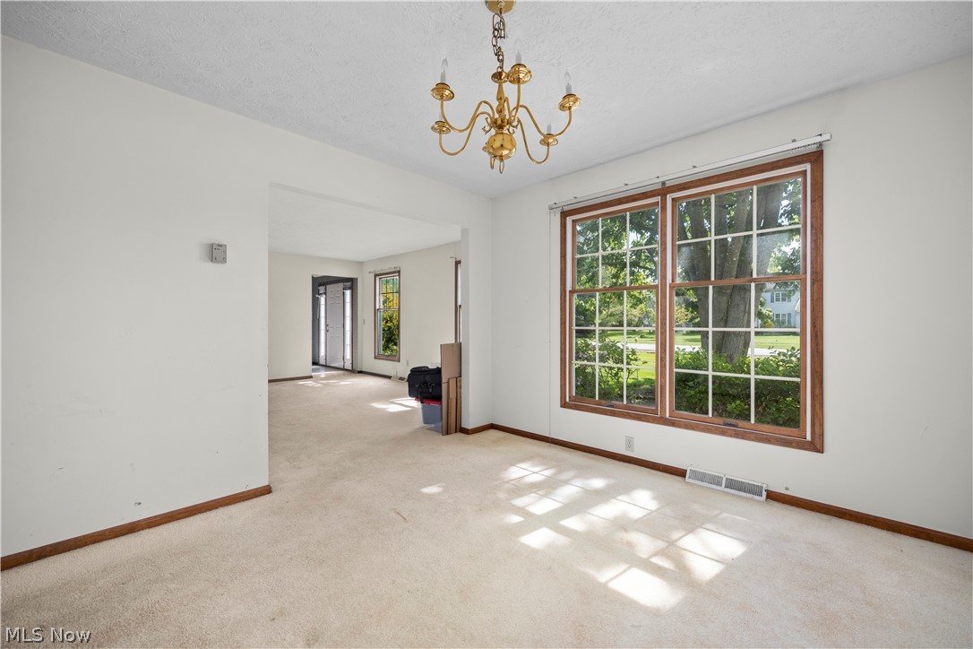722 Jaycox Road Avon Lake, OH 44012 - Photo 18 of 48 Bright interior room featuring a large double window with wood-finish trim, a brass-tone chandelier, and light-colored carpeting