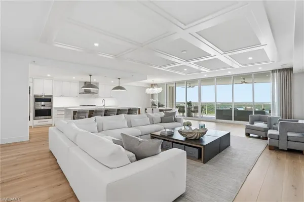 a living room with furniture kitchen view and a large window