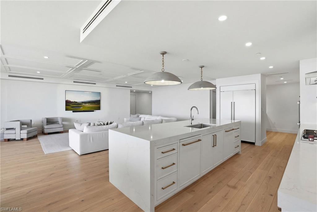 13945 Old Coast Road, Unit 803 Naples, FL 34110 - Photo 8 of 37 a large kitchen with stainless steel appliances kitchen island granite countertop a lot of counter space and wooden floors