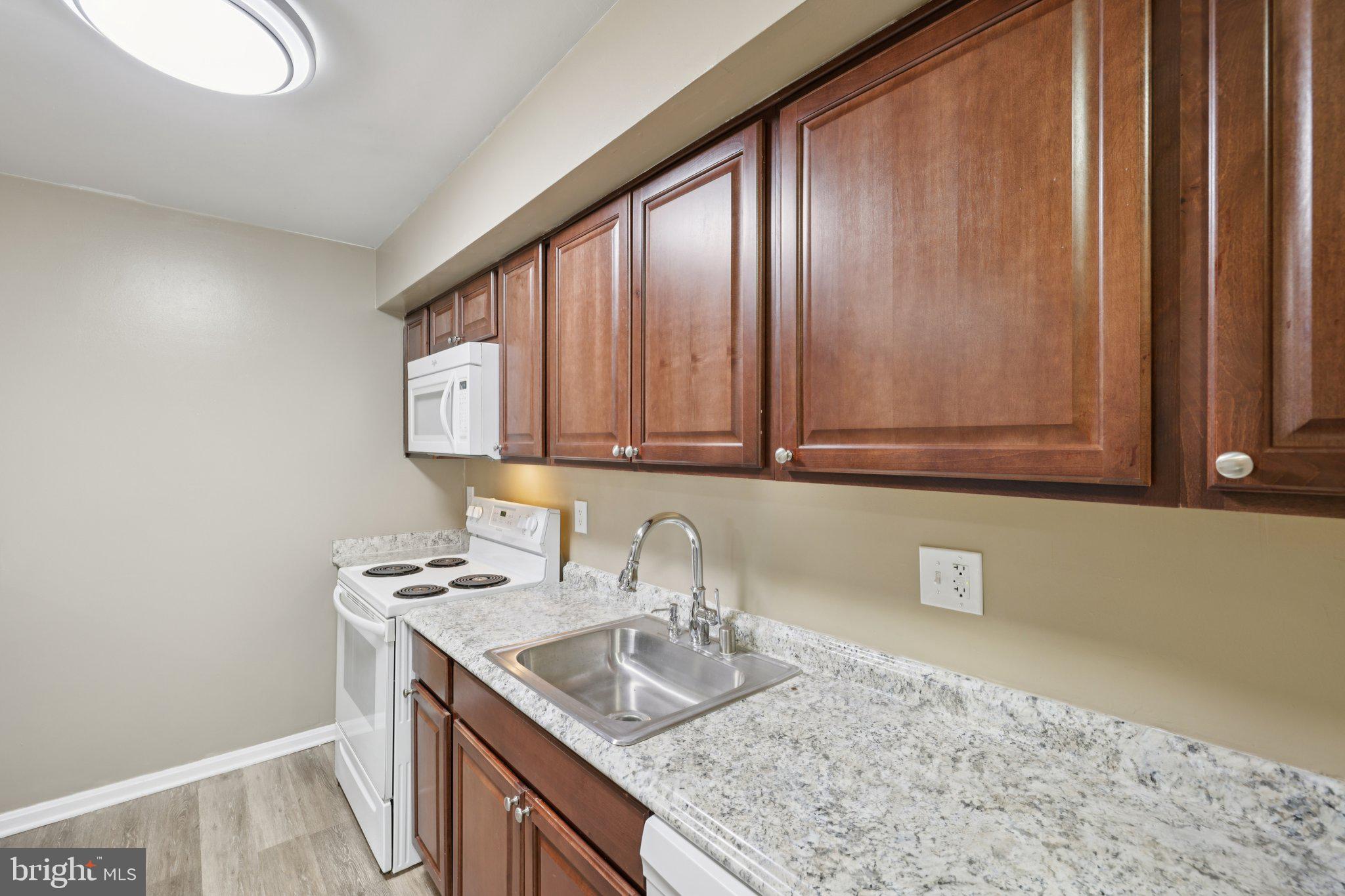 9075 North Laurel Road, Unit E Laurel, MD 20723 - Photo 17 of 28 a kitchen with granite countertop stainless steel appliances a sink and cabinets